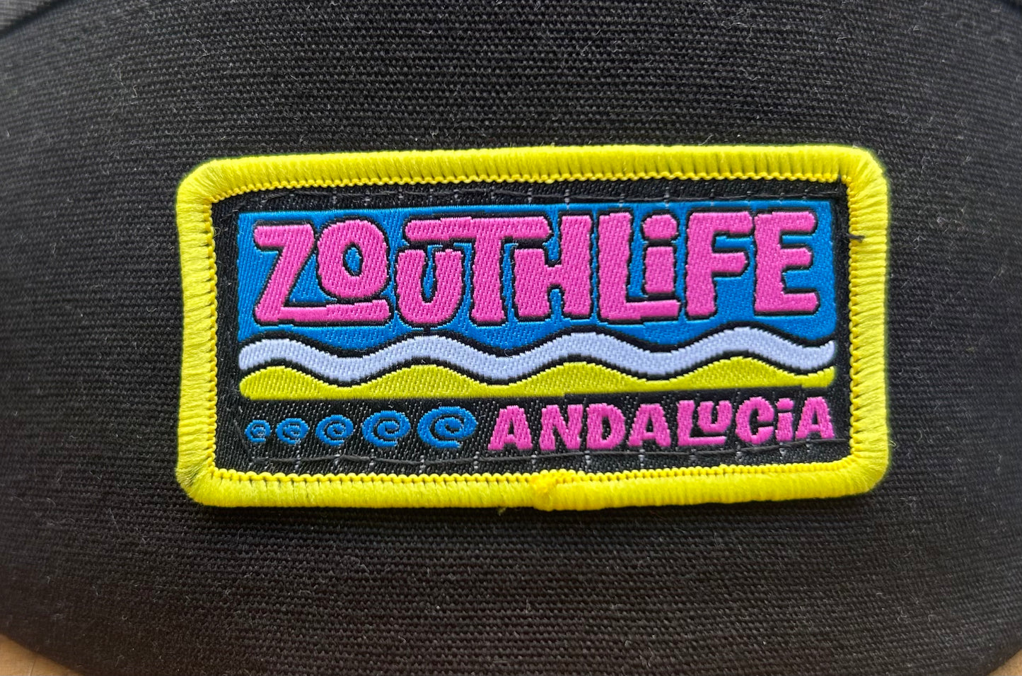 Vista detallada parche bordado gorra Zouth life en colores rosa, amarillo, azul y blanco.