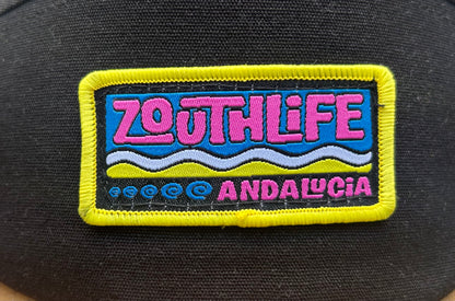 Vista detallada parche bordado gorra Zouth life en colores rosa, amarillo, azul y blanco. 