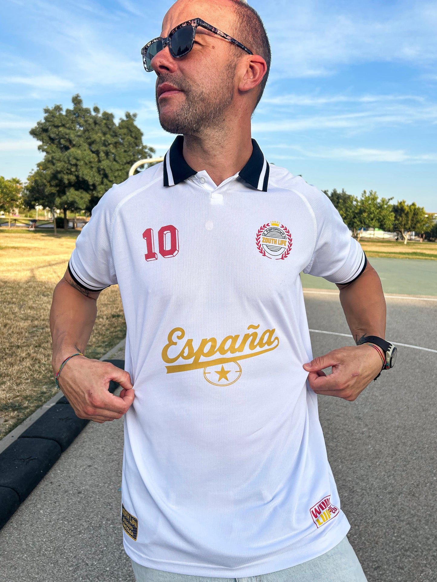 Polo retro de España Mundial 2026 en color blanco con cuello negro , modelo de frente vistiendo la edición limitada Cultura Castellana de la marca Zouthlife. Con logos estampados referentes  ESPAÑA Y EL MUNDIAL