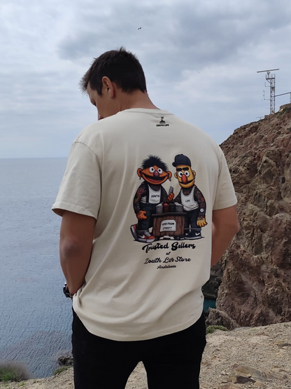 Modelo vistiendo la camiseta oversize con estampado en espalda de Epi & Blas Beige de 240 de gramaje en un entorno exterior de playa. La imagen muestra la caída de la prenda y su ajuste relajado, ideal para un look casual.