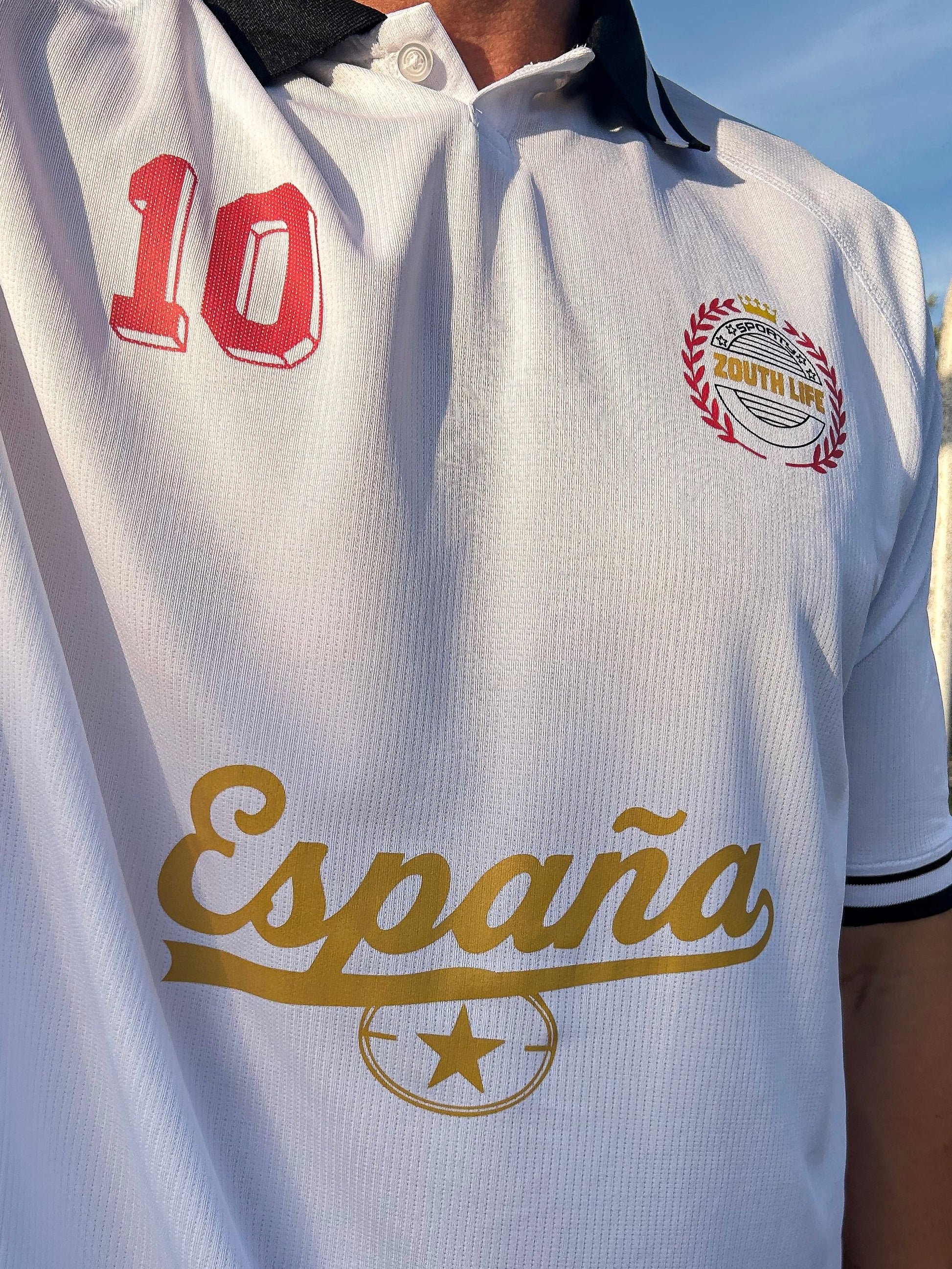 Polo retro de España Mundial 2026 en color blanco con cuello negro y detalles estampados en ambos lados y pecho, modelo de frente vistiendo la edición limitada Cultura Castellana de la marca Zouthlife.