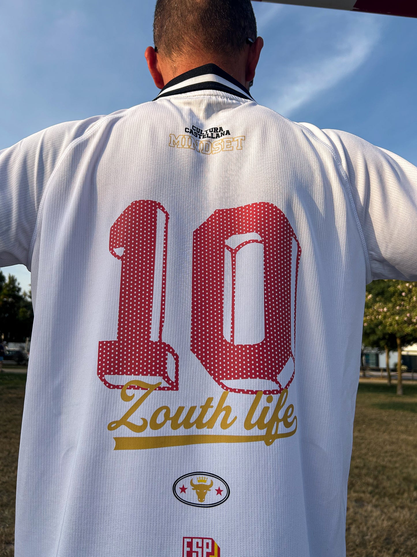 Fotografía de estilo campaña urbana de la parte trasera del polo retro de la selección española de Zouthlife, destacando el corte suelto.