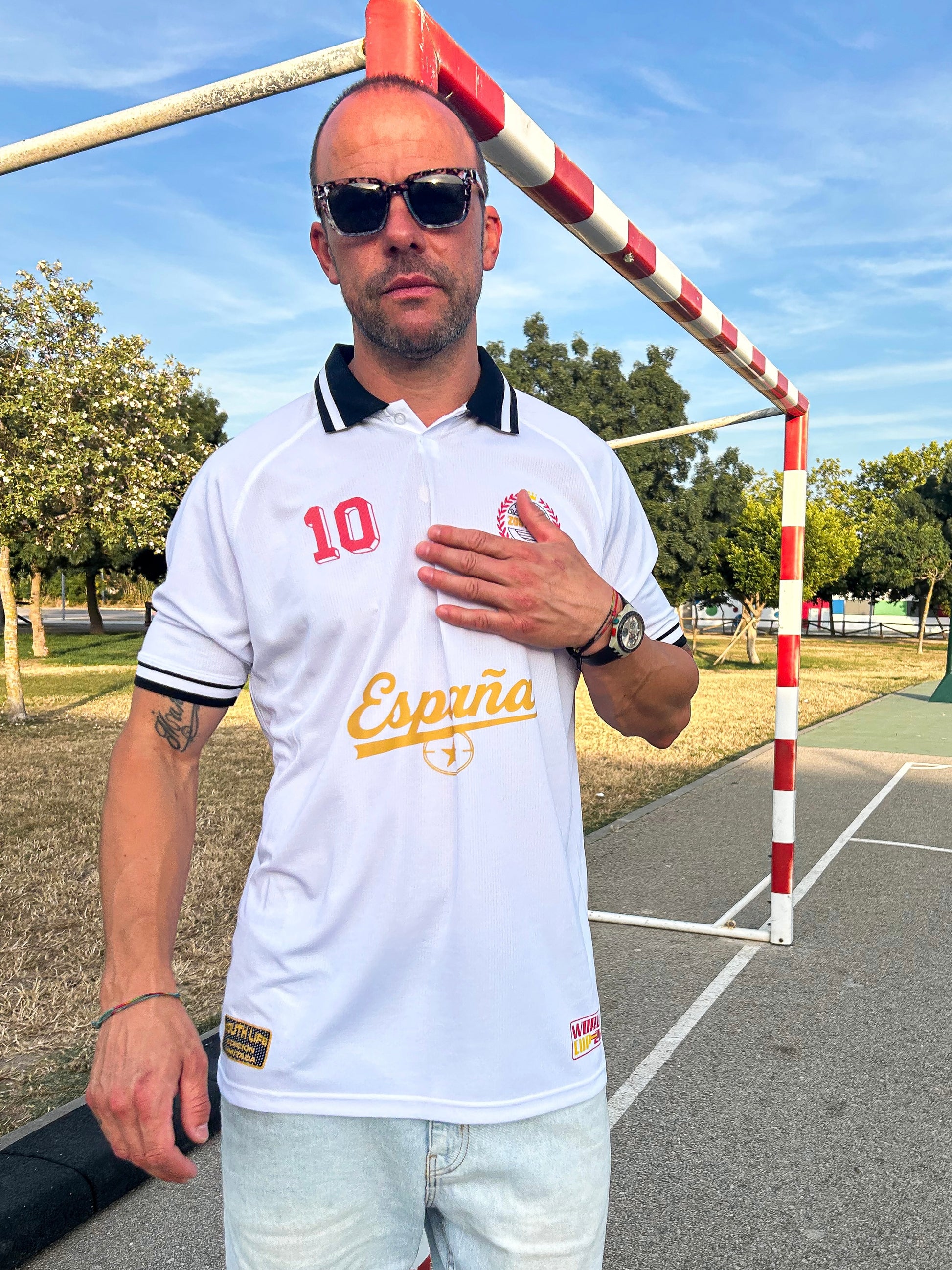 Modelo  con el Polo Retro España Mundial 2026 color blanco vista frontal combinado con bermudas vaqueras claras y zapatillas de estilo urbano blockecore.